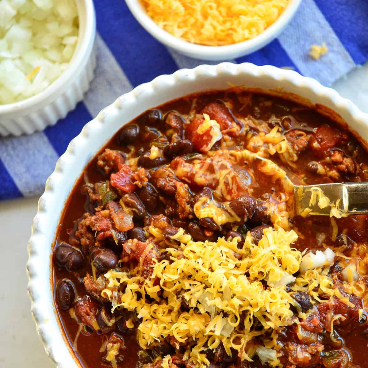 black bean chili with chorizo topped with cheese and onions in white bowl