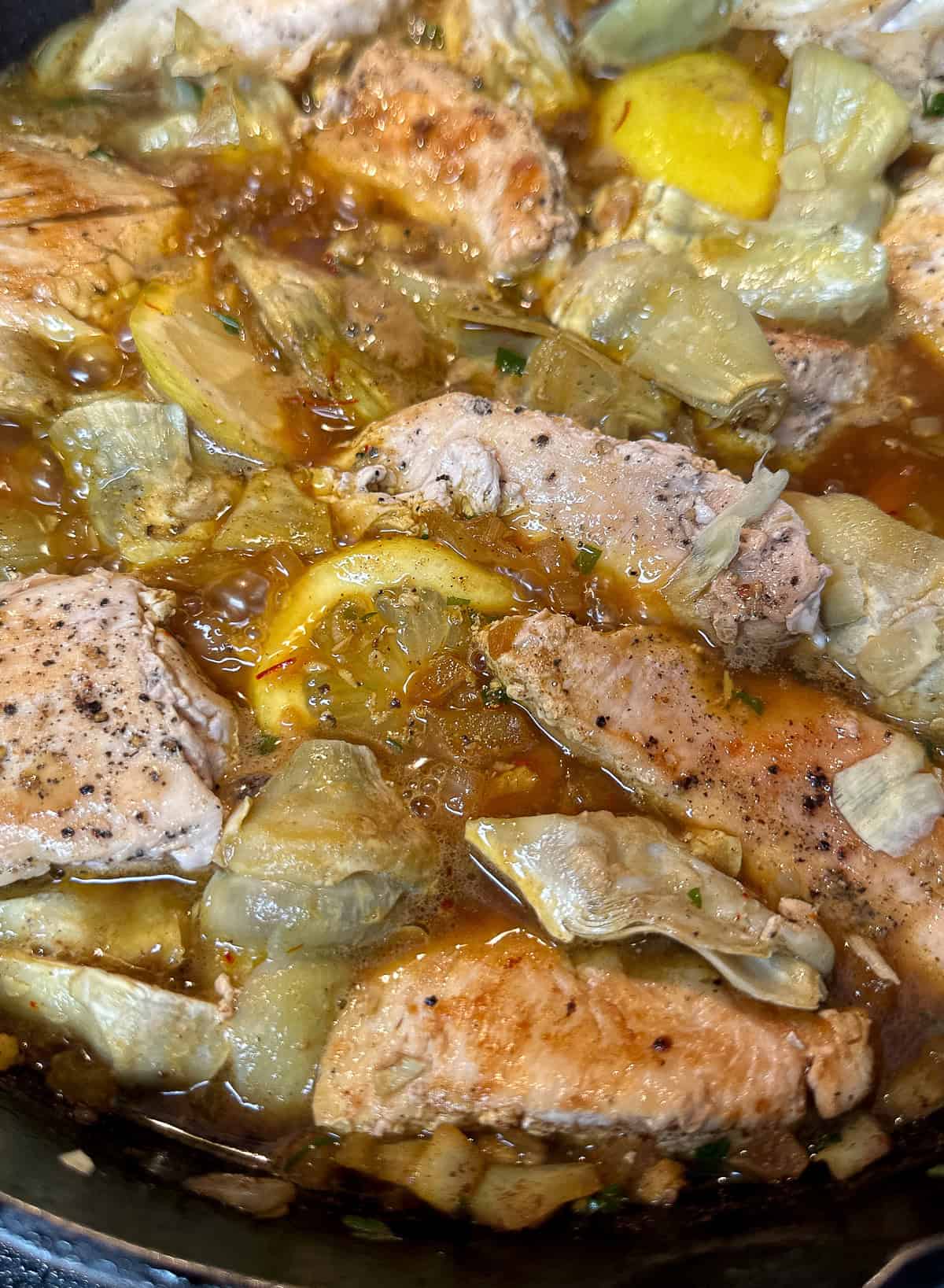 chicken breasts with artichokes and lemon cooking in skillet