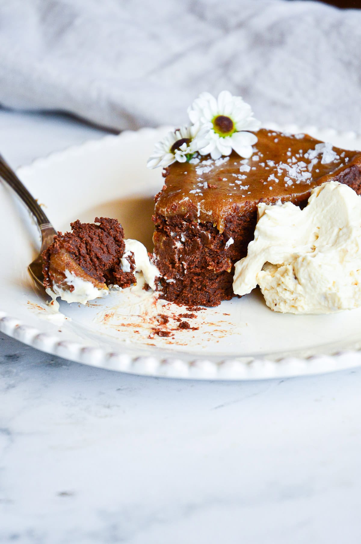 slice of date cake with chocolate with a bit of cake on fork  and whipped cream on plate