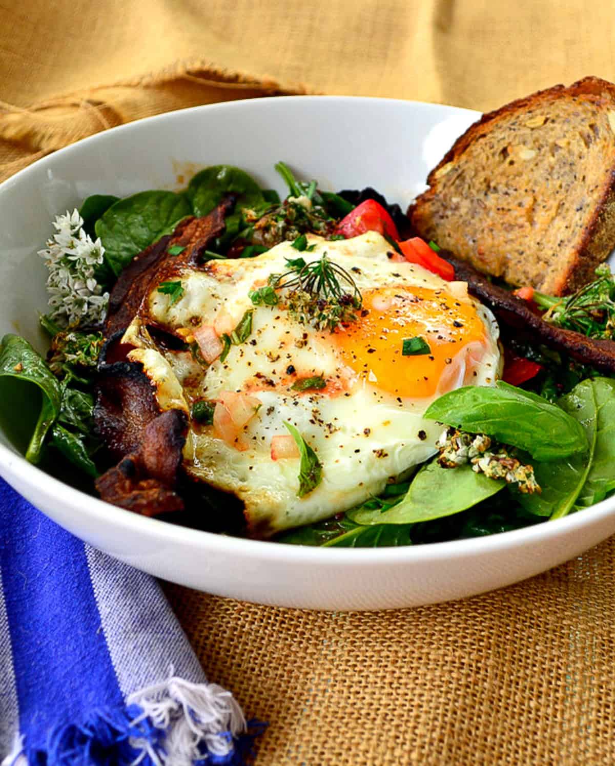 bacon and  egg spinach salad in white bowl