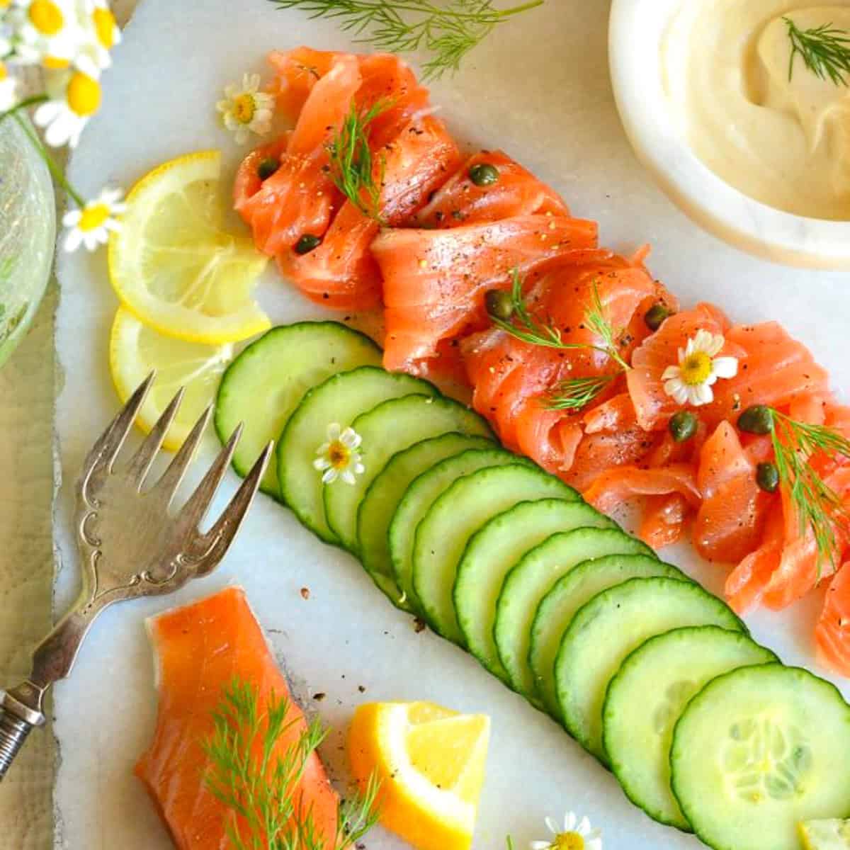 gravlax with capers and cucumbers and lemon and mayo with decorative fork and daisys is a great brunch menu idea