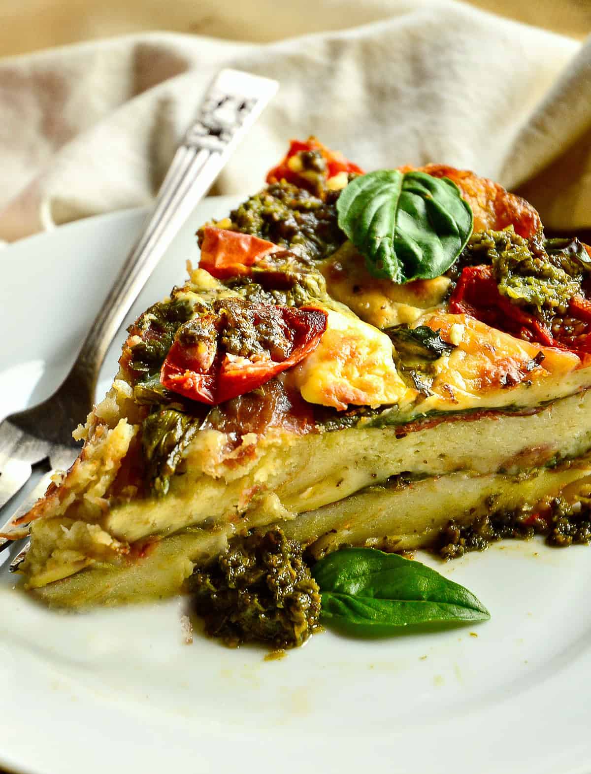 slice of summer pesto breakfast strata on white plate with fork