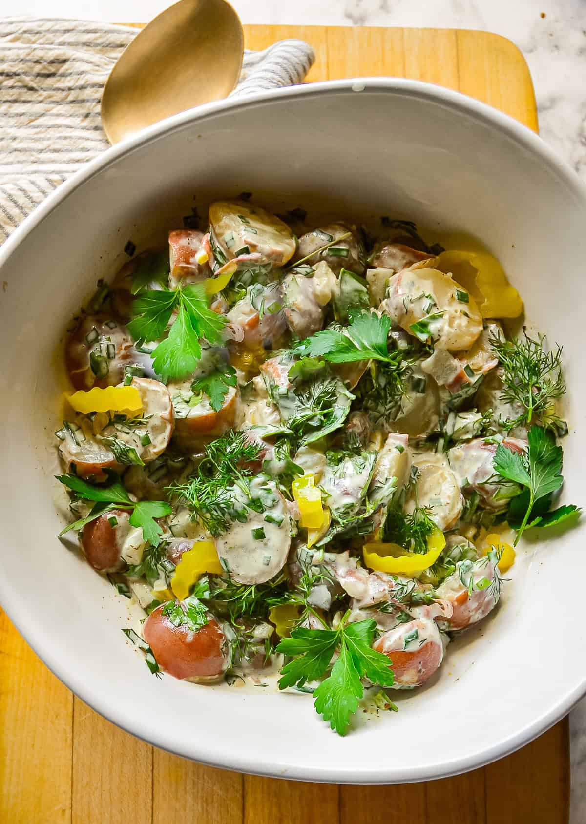 bowl of pickle potato salad with pepperoncini and fresh herbs made with  red potatoes