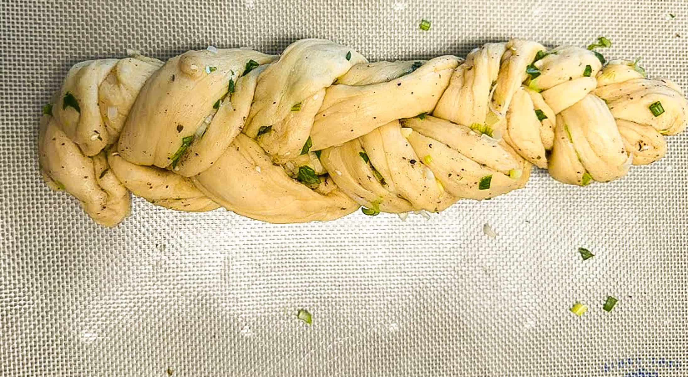 unbaked braided challah loaf on silpat pad